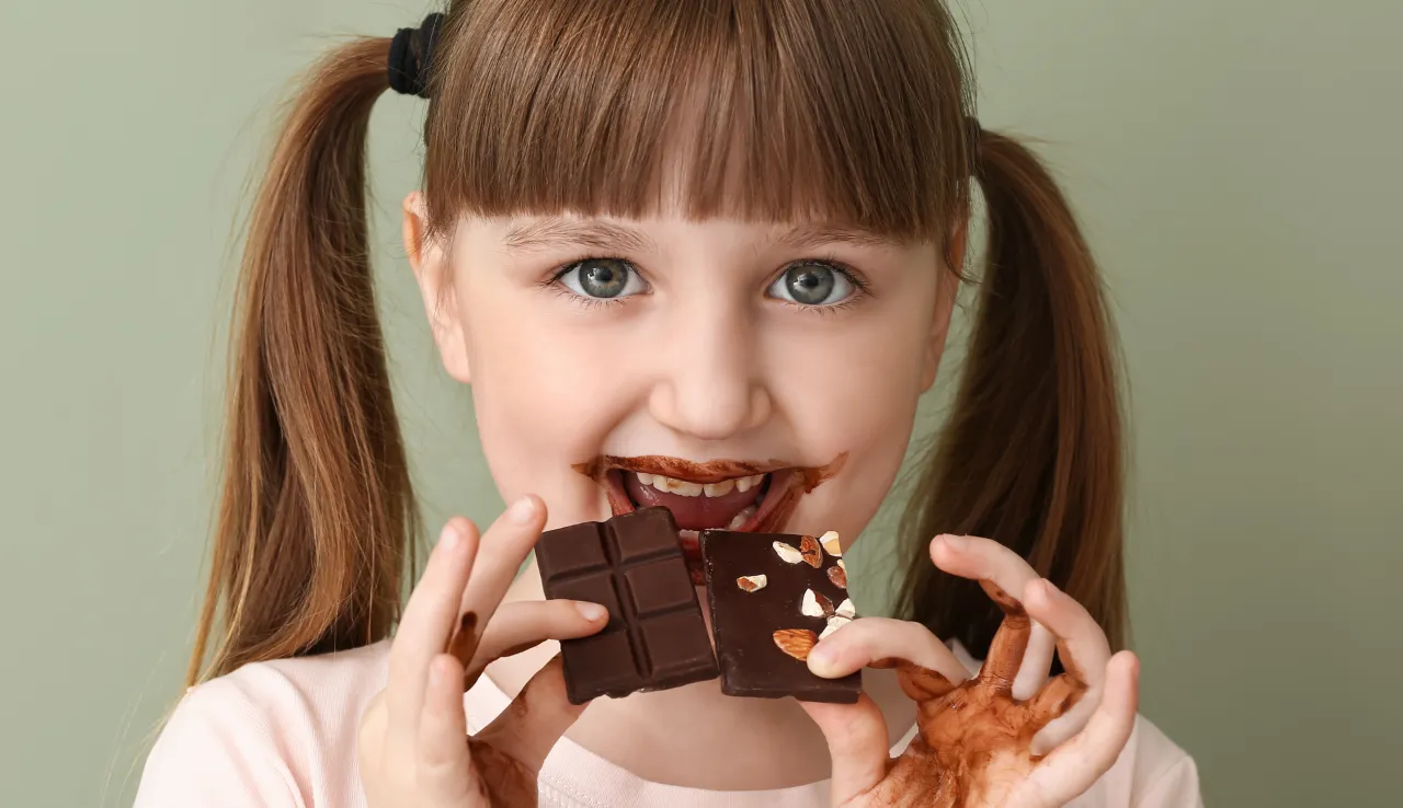 Dziecko jedzące czekoladę z zaniepokojoną matką