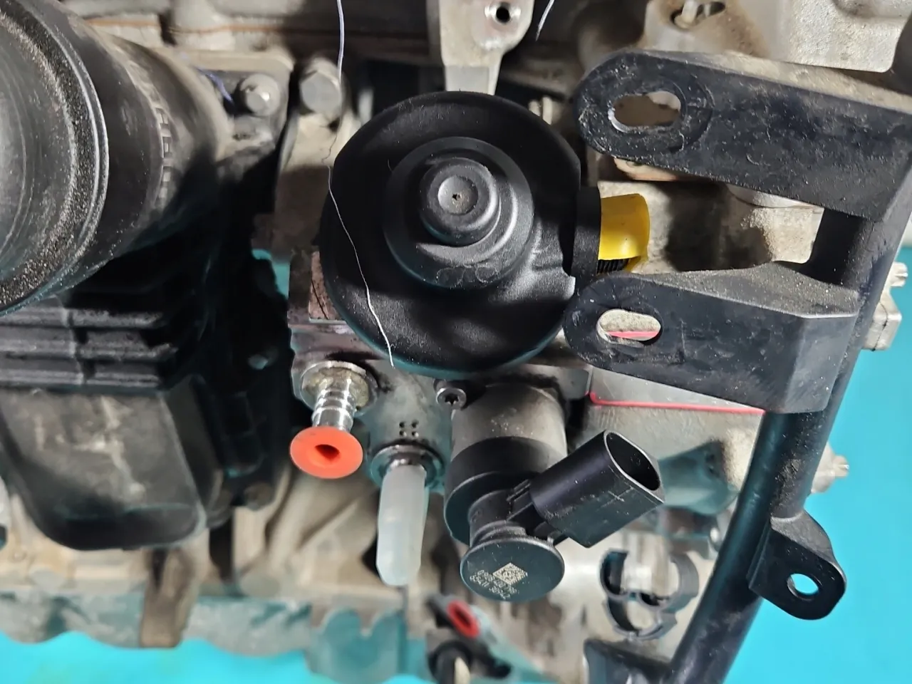 Widok na elementy silnika, gdzie znajduje się pompa paliwa Toyota RAV4. Widoczne przewody i złącza.