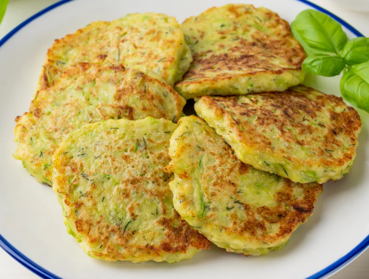 Placki z cukinii na talerzu, złociste i apetyczne. Idealne z jogurtem lub śmietaną – jaki sos do plackow z cukinii?