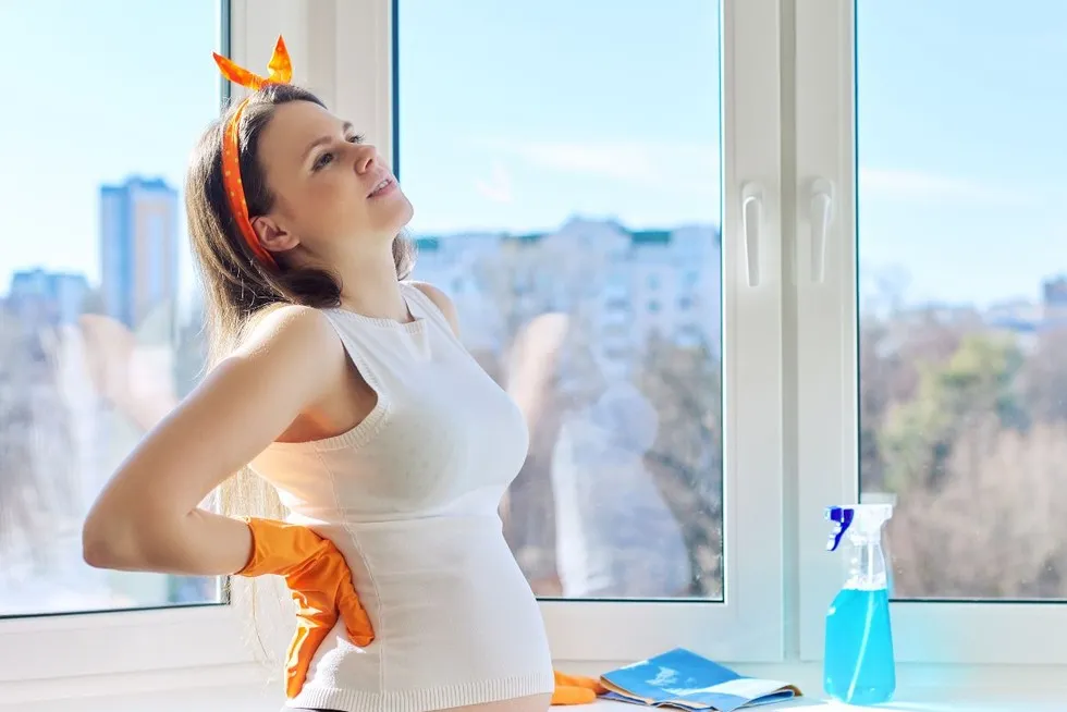 zamyślona kobieta w ciąży patrząca przez czyste okno