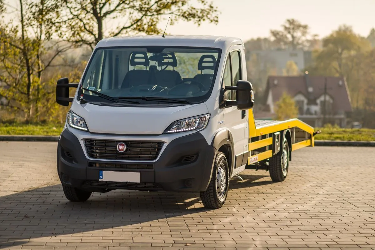 Biała autolaweta Fiat Ducato z żółtym najazdem, idealna do wynajmu dla posiadaczy prawa jazdy kat. C.