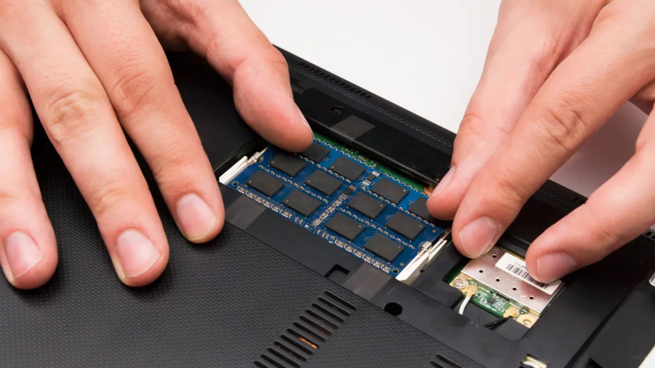 Dłonie montują moduł RAM, usprawniając działanie laptopa.