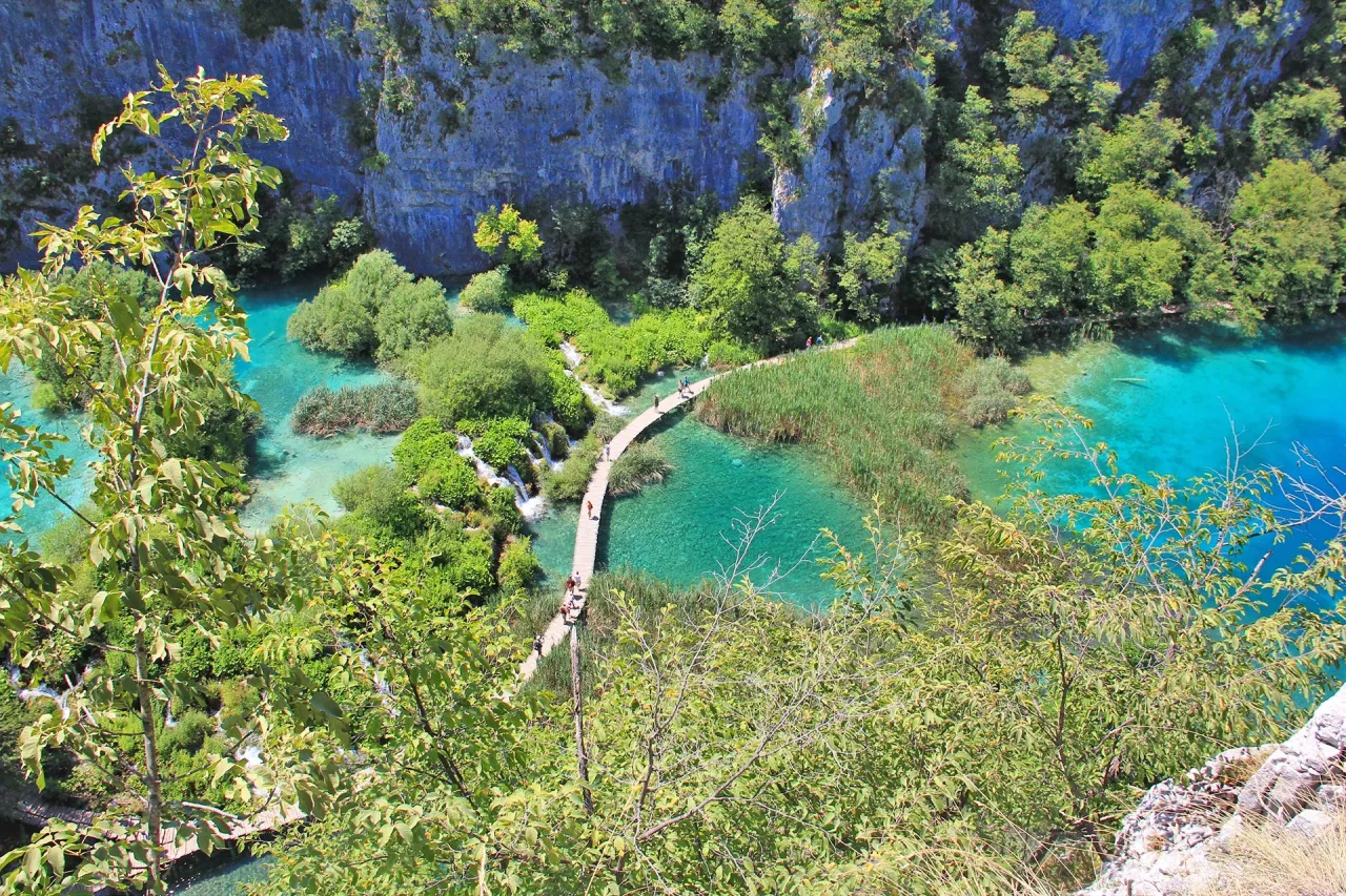 Chorwacja najpiękniejsze miejsca: spacer po drewnianej kładce wśr&oacute;d turkusowych jezior i bujnej zieleni Parku Narodowego Jezior Plitwickich.