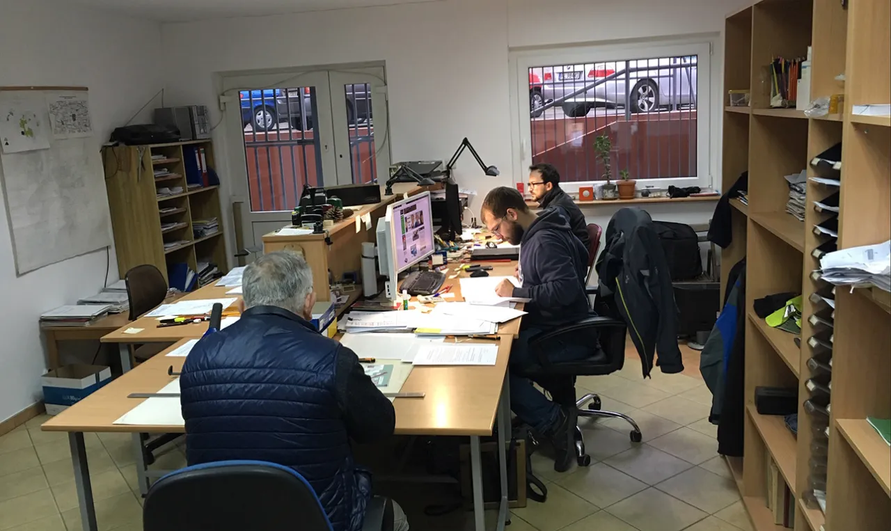 geodeta pracujący przy biurku z mapami i dokumentami