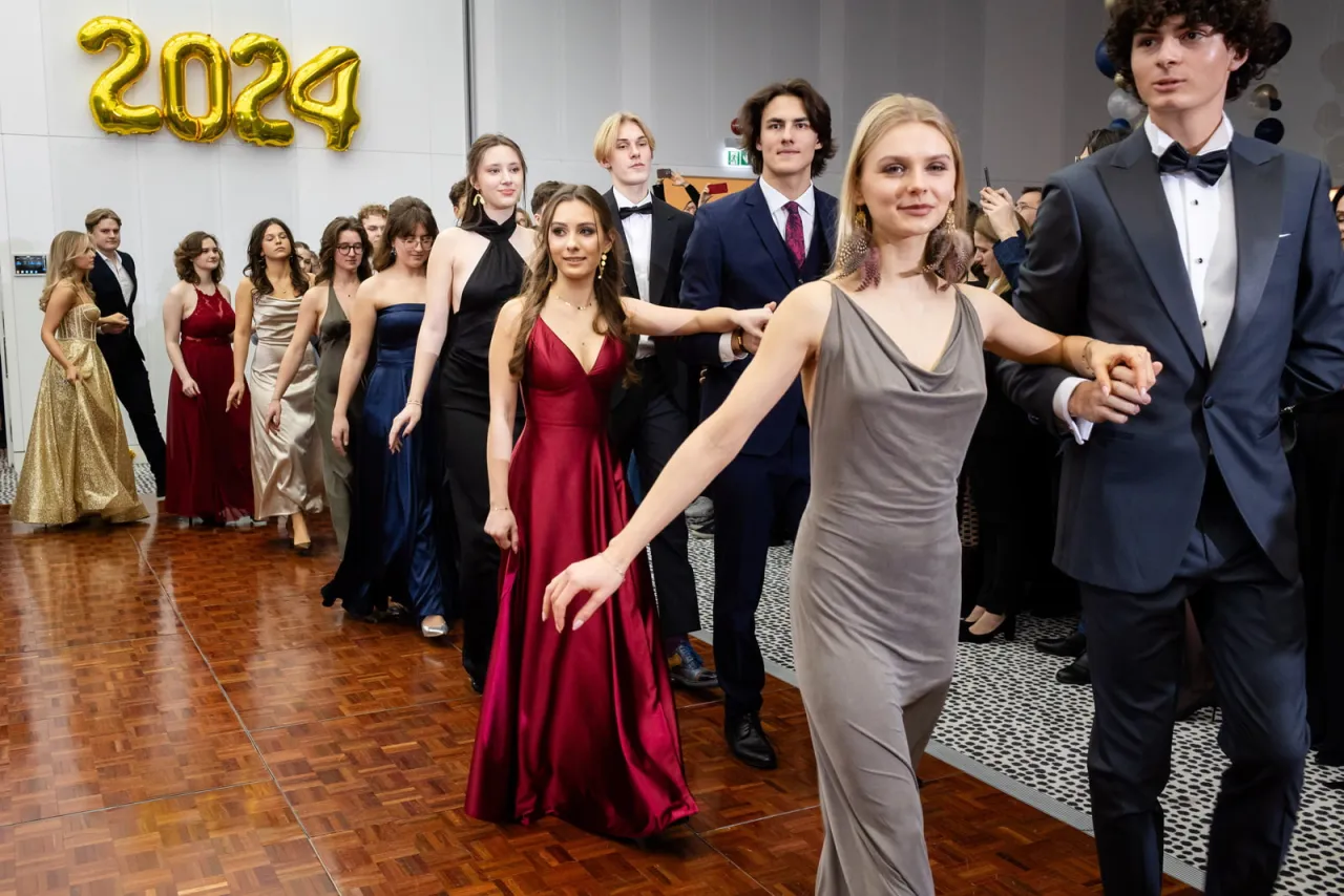 Młodzi ludzie w eleganckich strojach tańczą na parkiecie. Zastanawiasz się, ile kosztuje fotograf na studniówkę?