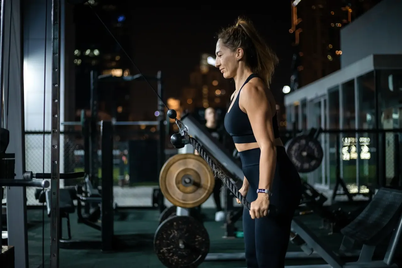 Kobieta ćwiczy na siłowni, zastanawiając się, ile zarabia siłownia z kartą multisport.