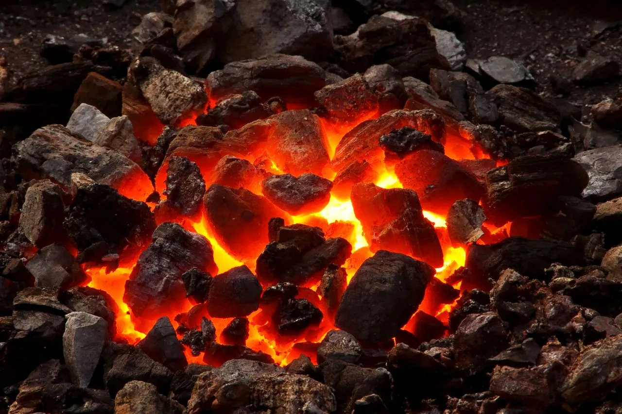 Żarzący się stos węgla, idealny jako brykiet czy węgiel do pieca, rozświetla ciemność.