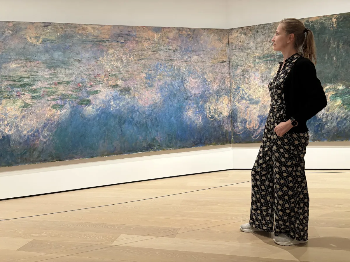 Kobieta w kropkowanym kombinezonie podziwia obraz