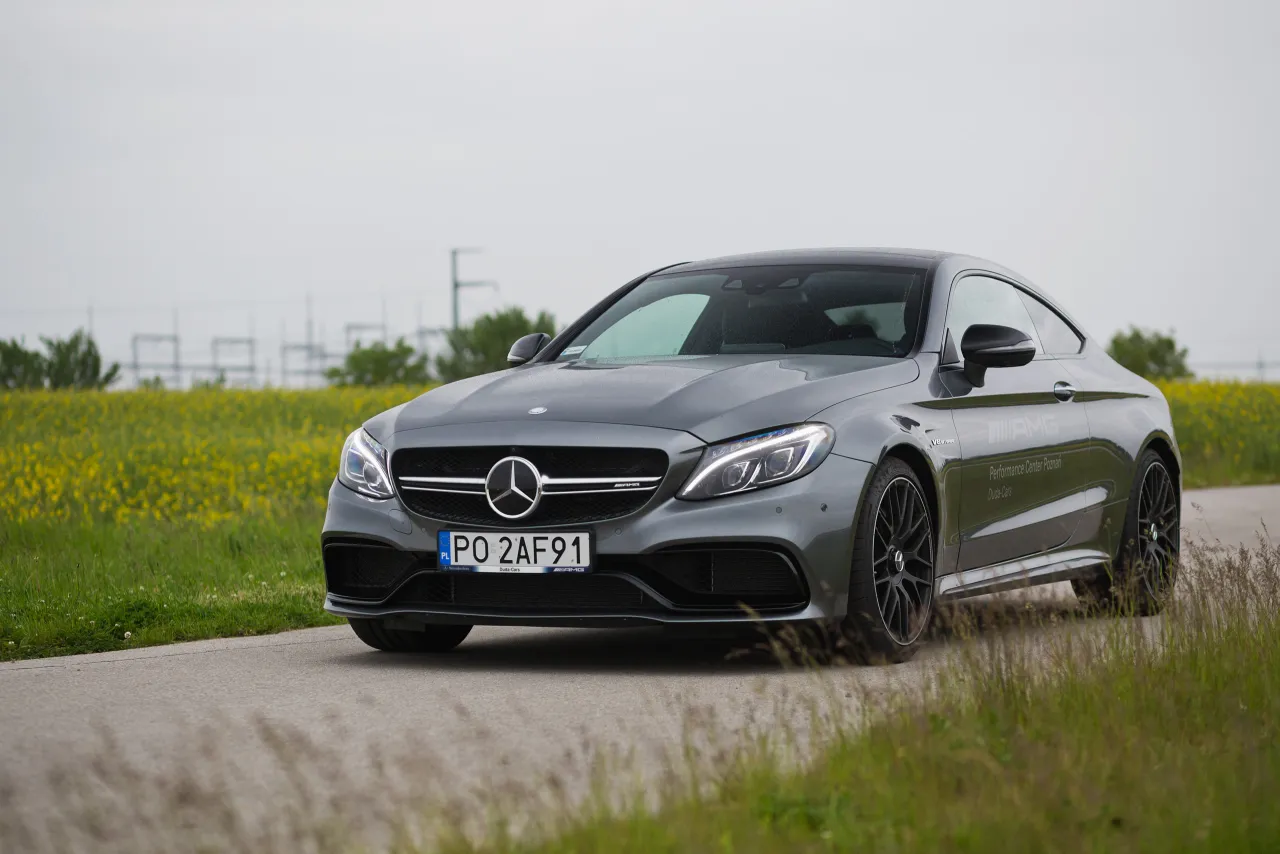 Szary Mercedes-AMG C63 Coupe na tle kwitnącego pola.