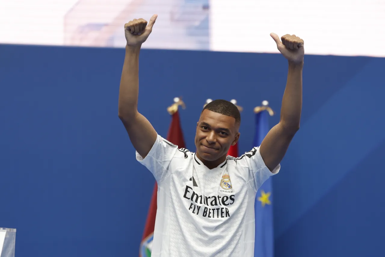 Mbappé w białej koszulce z podniesionymi rękami, radośnie pozuje. Czy to znak, gdzie gra Mbappé?