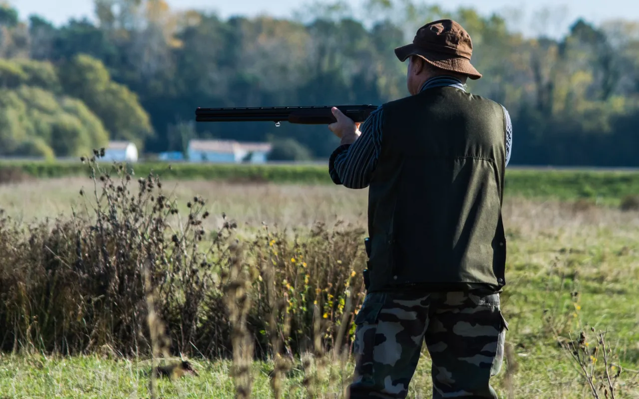 Myśliwy w kapeluszu i kamizelce celuje z broni. Czy myśliwi przechodzą psychotesty?