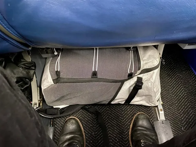 personne plaçant un petit sac à dos sous un siège d'avion easyJet