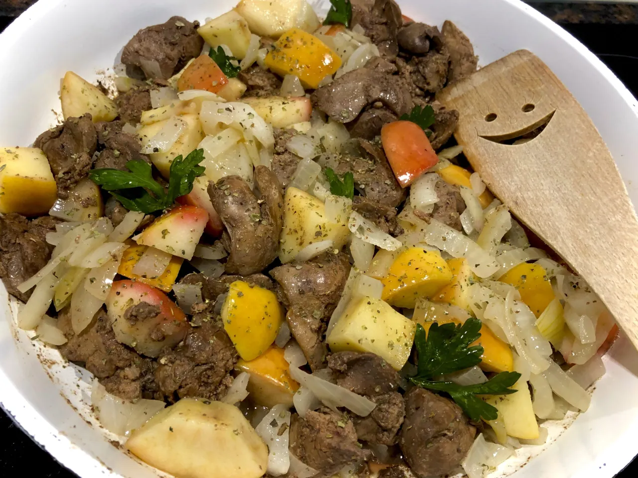 Pyszna watrobka drobiowa przepis na patelni z jabłkami, cebulą i papryką. Uśmiechnięta łopatka sugeruje, że danie jest gotowe!