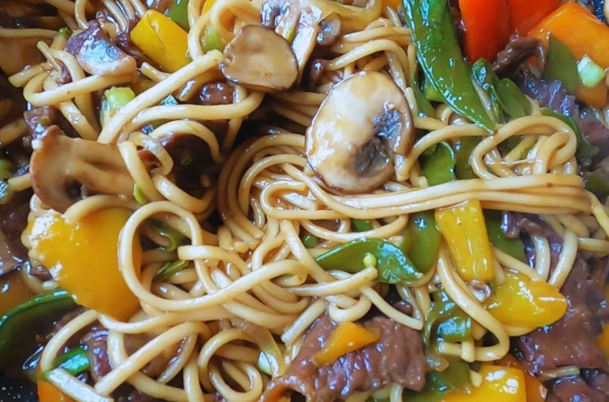 Udon z wołowiną przepis: sycące danie z grubym makaronem, kawałkami wołowiny, pieczarkami, papryką i zielonym groszkiem w sosie.