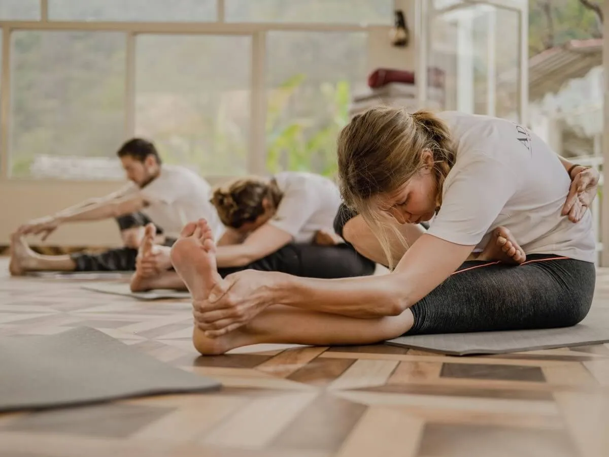 Kobieta ćwicząca jogę obok bieżni i ciężar&oacute;w