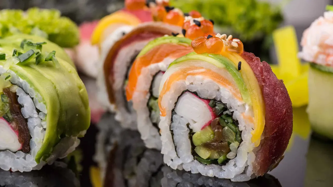 Kolorowe rolki sushi i sashimi z łososiem, awokado i ikrą.