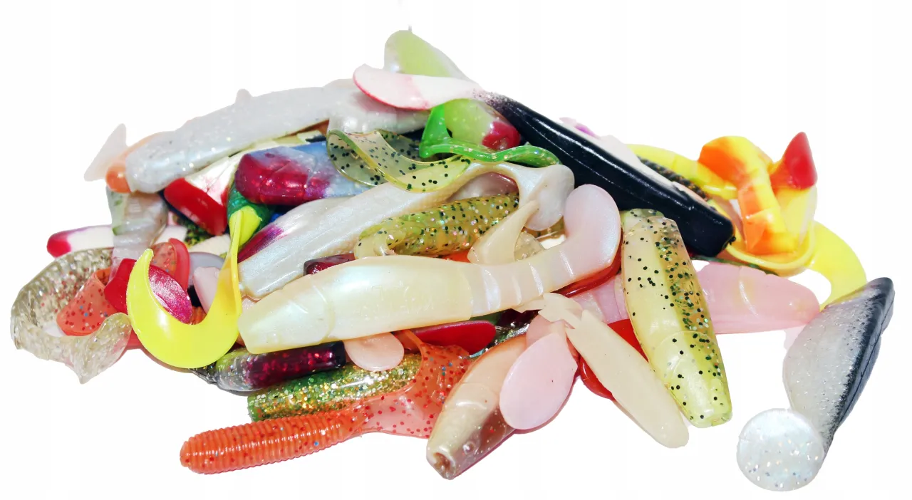 Kolorowy stos gumowych przynęt na spinning: rippery, kopyta, twistery w odcieniach bieli, ż&oacute;łci, zieleni, pomarańczy i czerwieni.