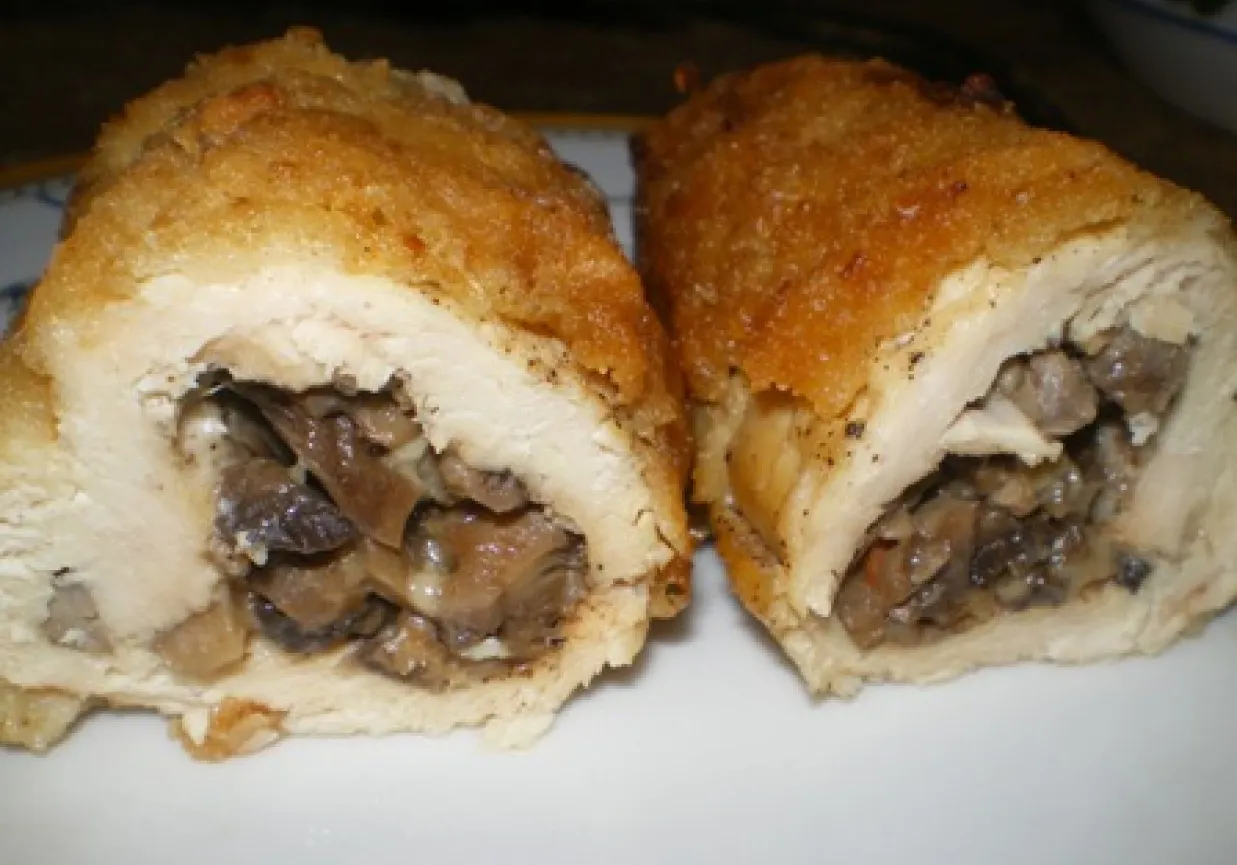 Dwie złociste roladki drobiowe z serem i grzybami, przekrojone, ukazujące soczyste nadzienie.