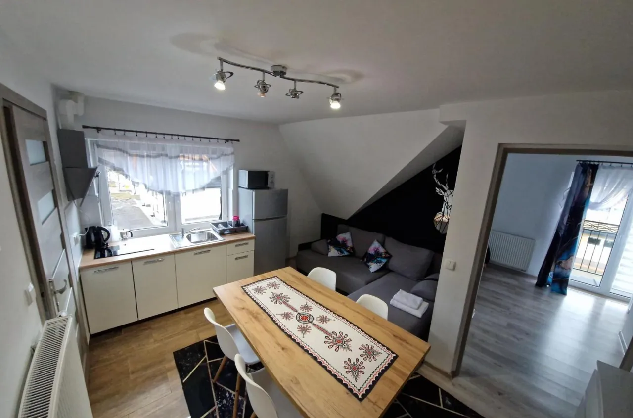 Przytulny apartament Wierchy Zakopane: aneks kuchenny, salon z sofą i stołem, widok na góry.