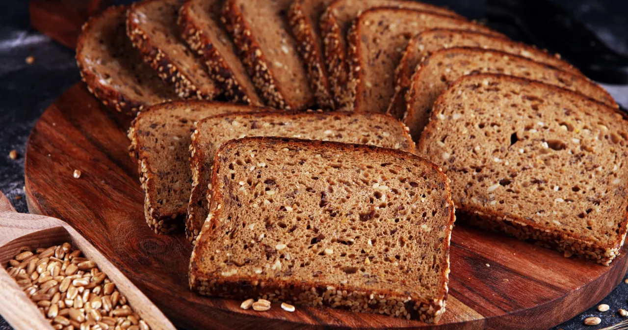 kobieta je kanapkę z chleba żytniego, uśmiechnięta, zdrowa dieta