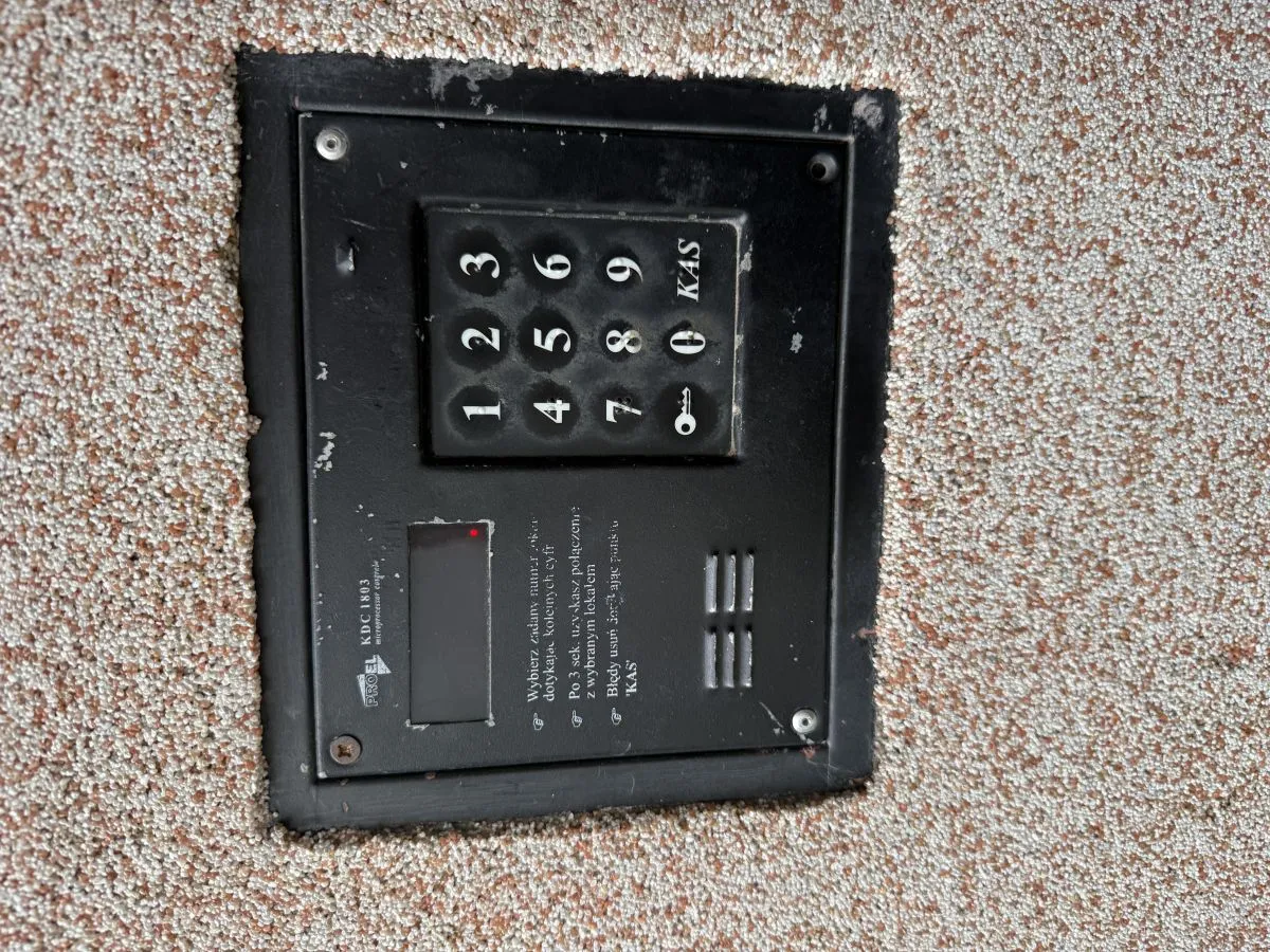 Panel domofonu z klawiaturą numeryczną i instrukcją, jak otworzyć drzwi domofonem.