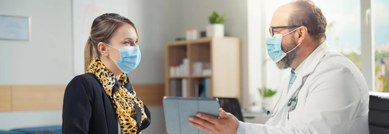 Osoby w maseczkach w poczekalni przychodni lub szpitala