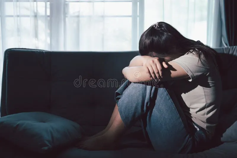 smutna osoba siedząca samotnie na kanapie w salonie