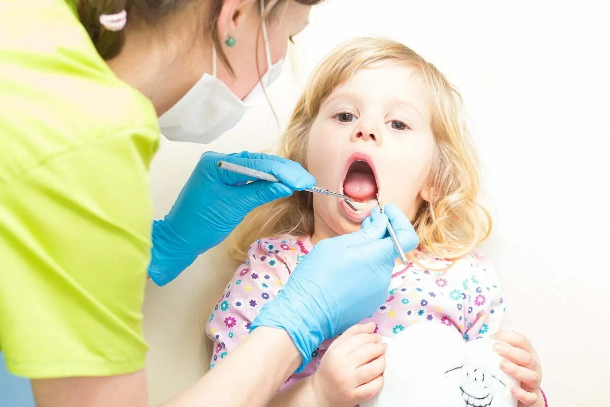 Dziecko bawi się w dentystę z misiem