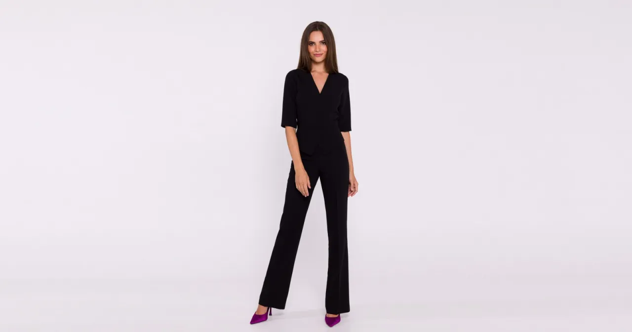 Elegancki czarny kombinezon z kopertowym dekoltem i szerokimi nogawkami. Czy kombinezon pogrubia? Ten model podkreśla sylwetkę, nie dodając objętości.