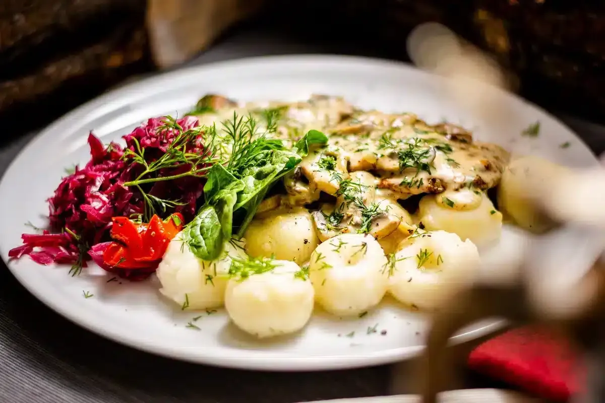 Pyszny obiad w Warszawie: ziemniaki, sos grzybowy, surówka z czerwonej kapusty i zielona sałata. Idealne miejsce, gdzie na obiad w Warszawie.