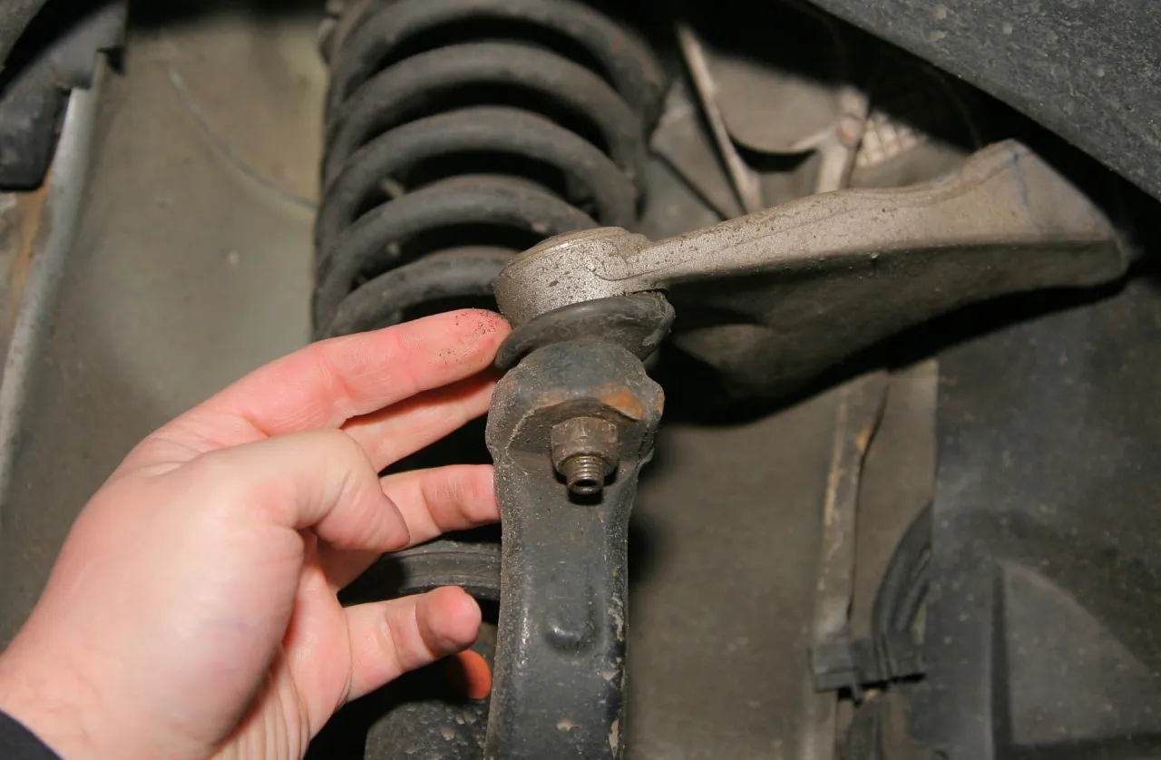 Dłoń sprawdza stan sworznia wahacza, kluczowy element do prawidłowego działania zawieszenia.