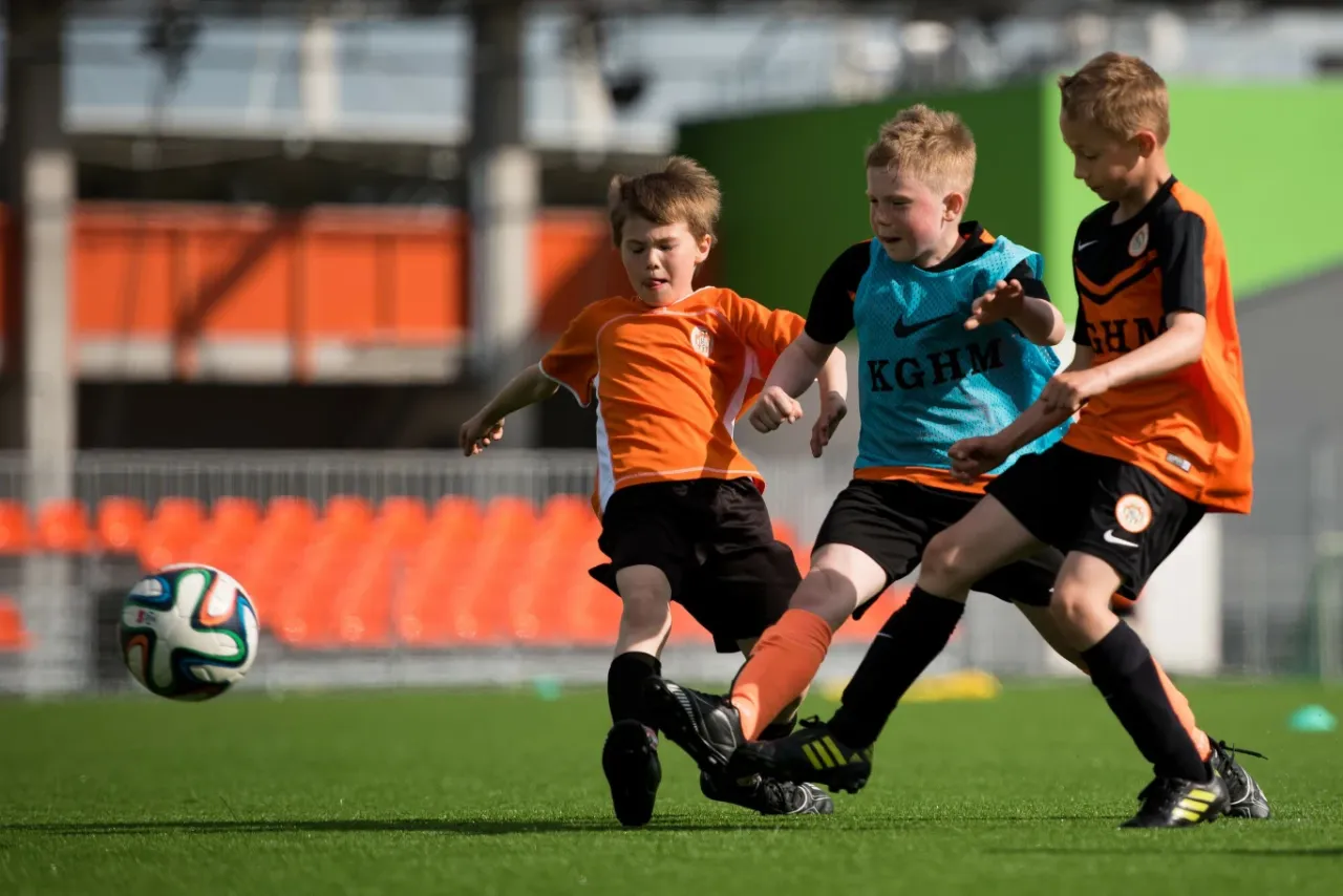 Trzech chłopc&oacute;w walczy o piłkę na boisku. Czy to początek drogi, jak dostać się do ekstraklasy?