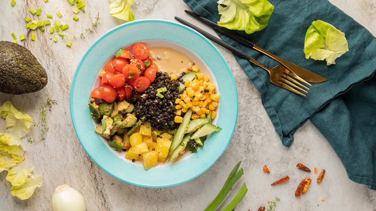 Kolorowy bowl pełen świeżych warzyw: pomidorki, awokado, kukurydza, og&oacute;rek, czarna soczewica i ananas. Idealny na zdrowy lunch.