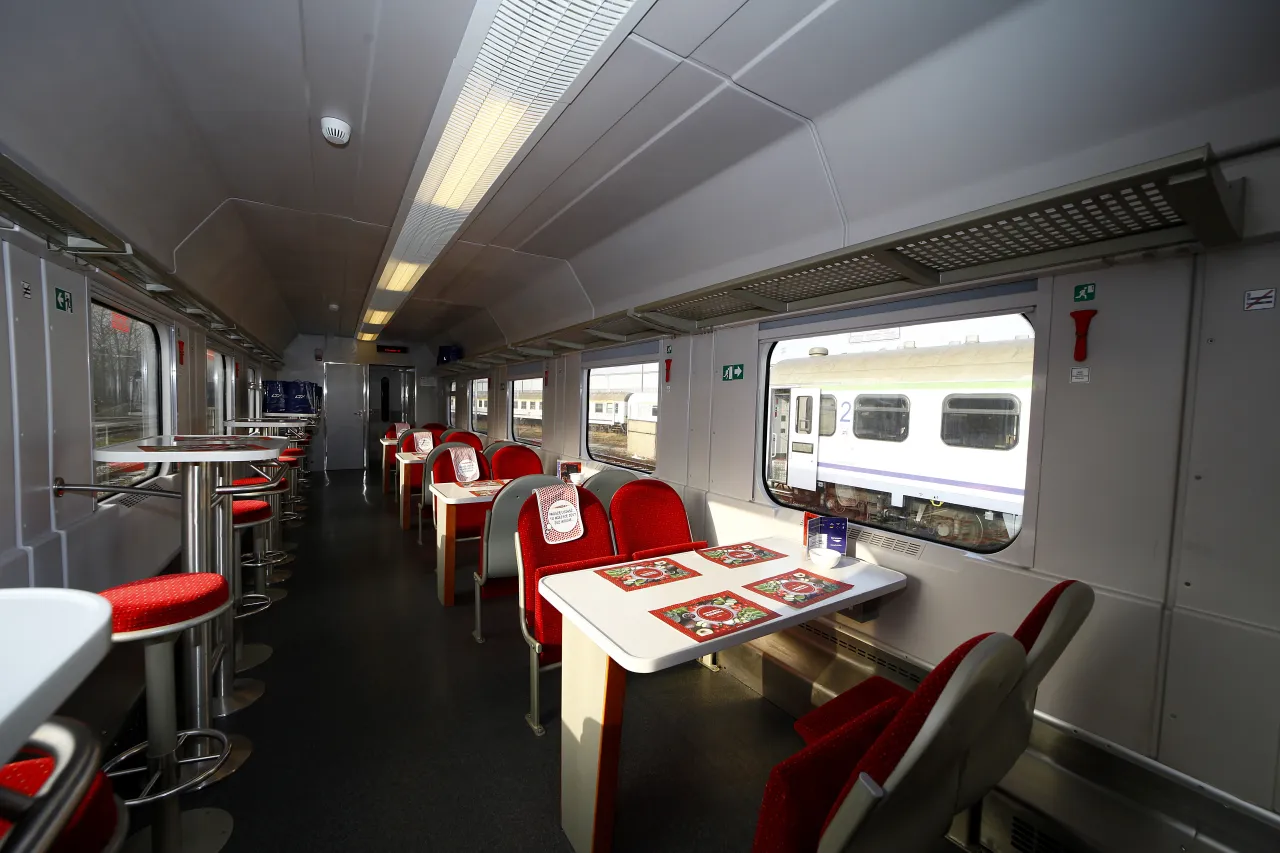 Wnętrze wagonu PKP Intercity z czerwonymi siedzeniami i stolikami. Idealne miejsce na podr&oacute;ż.