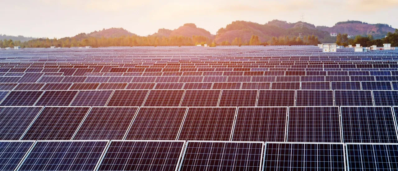 Ogromne pole paneli słonecznych w świetle zachodzącego słońca. Od kiedy można instalować 150 kw bez pozwolenia na budowę?
