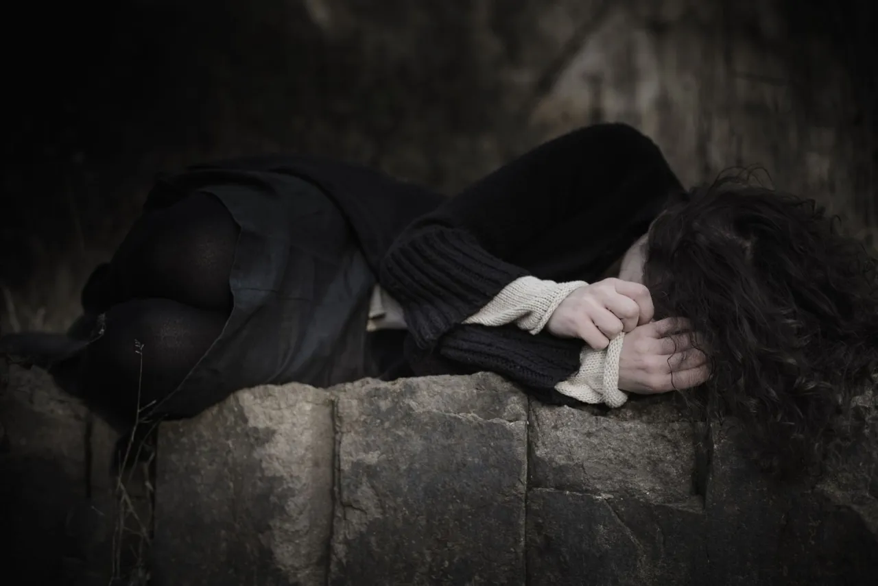 Osoba zamyślona, podr&oacute;żująca pociągiem lub autobusem, z walizką obok siebie