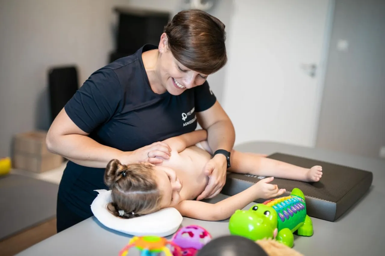 Fizjoterapeuta dziecięcy badający dziecko, rodzic z dzieckiem u lekarza, przyjazna atmosfera gabinetu