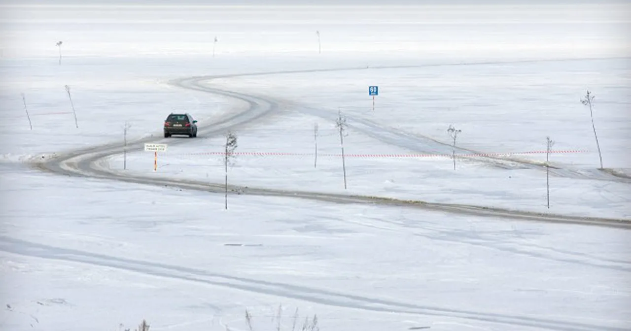 Samochód jedzie po lodowej drodze, kiedy Bałtyk zamarzł całkowicie. W oddali widać znak z numerem 60.