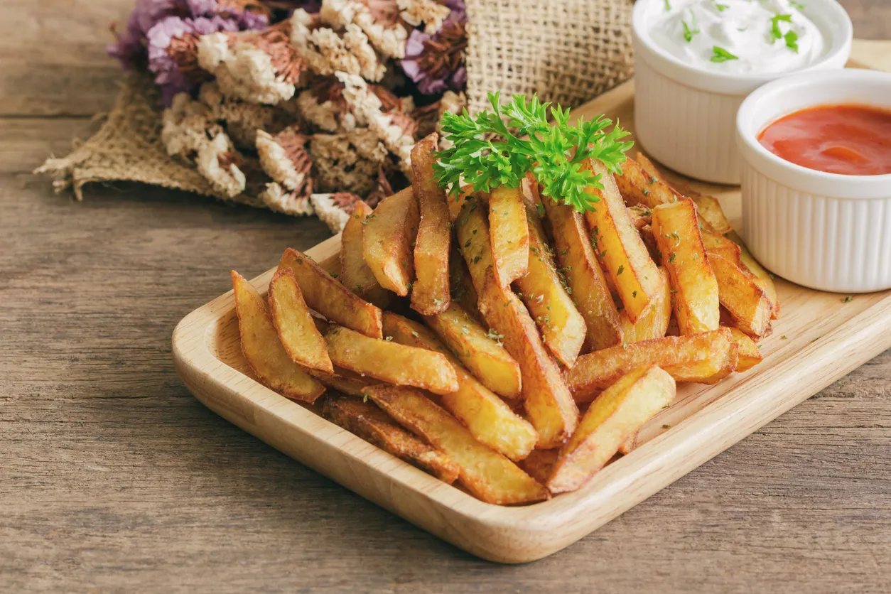 Złociste frytki, idealne do pieczenia, podane z ketchupem i sosem. Prosty sposób, jak piec frytki, by były chrupiące.