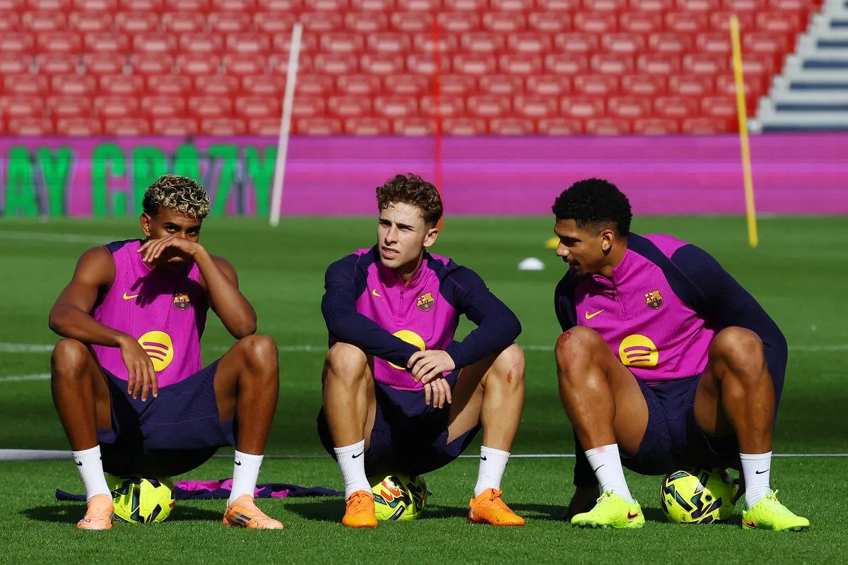 Trzech piłkarzy FC Barcelony w r&oacute;żowych strojach siedzi na murawie, zastanawiając się, jak dostać się do ekstraklasy.