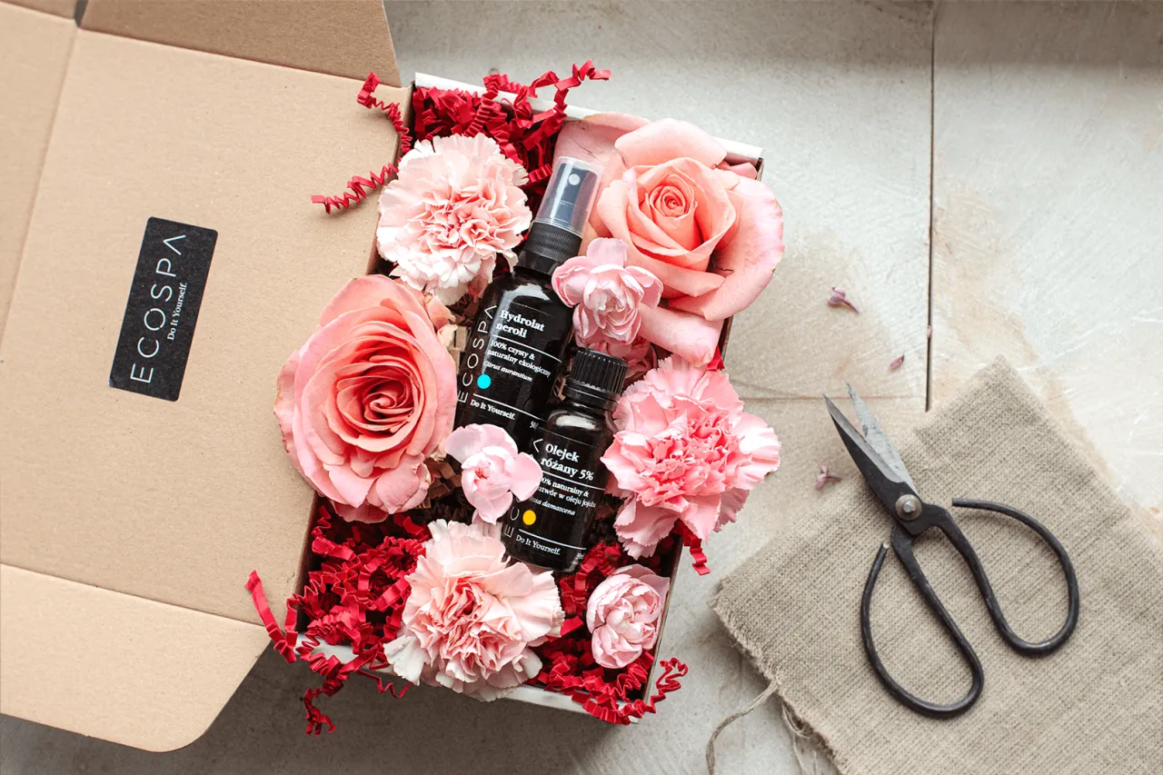 Kobieta aplikująca balsam do ciała, zadowolona, w tle kwiaty