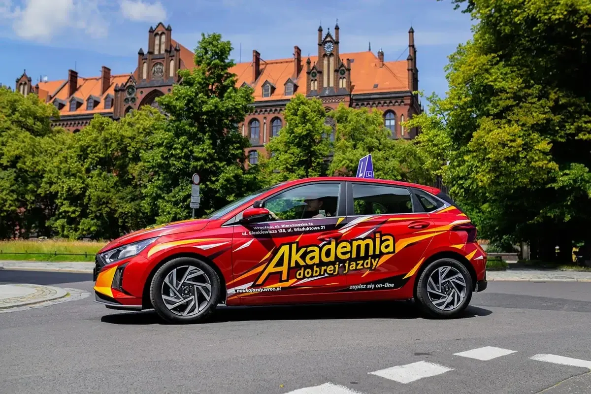 Czerwony samoch&oacute;d Akademii Dobrej Jazdy z napisem 