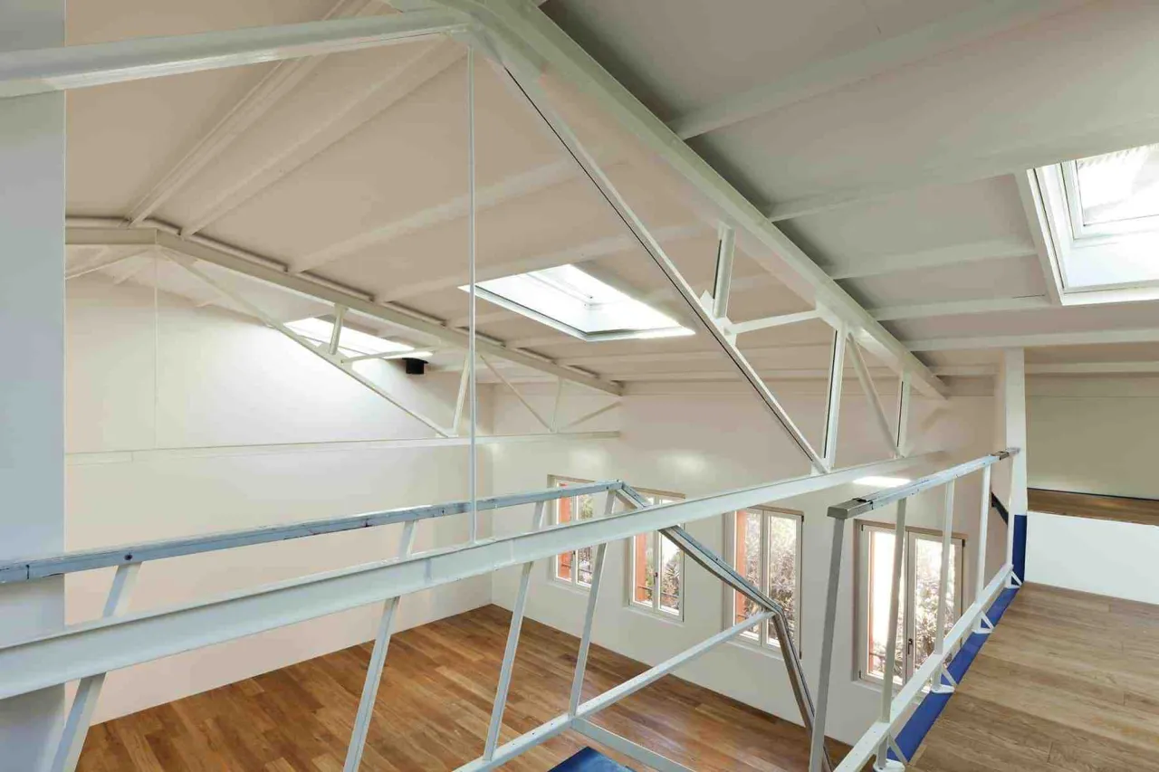 Widok z antresoli, kt&oacute;ra jest dodatkową kondygnacją, na jasne wnętrze z drewnianą podłogą i oknami dachowymi.