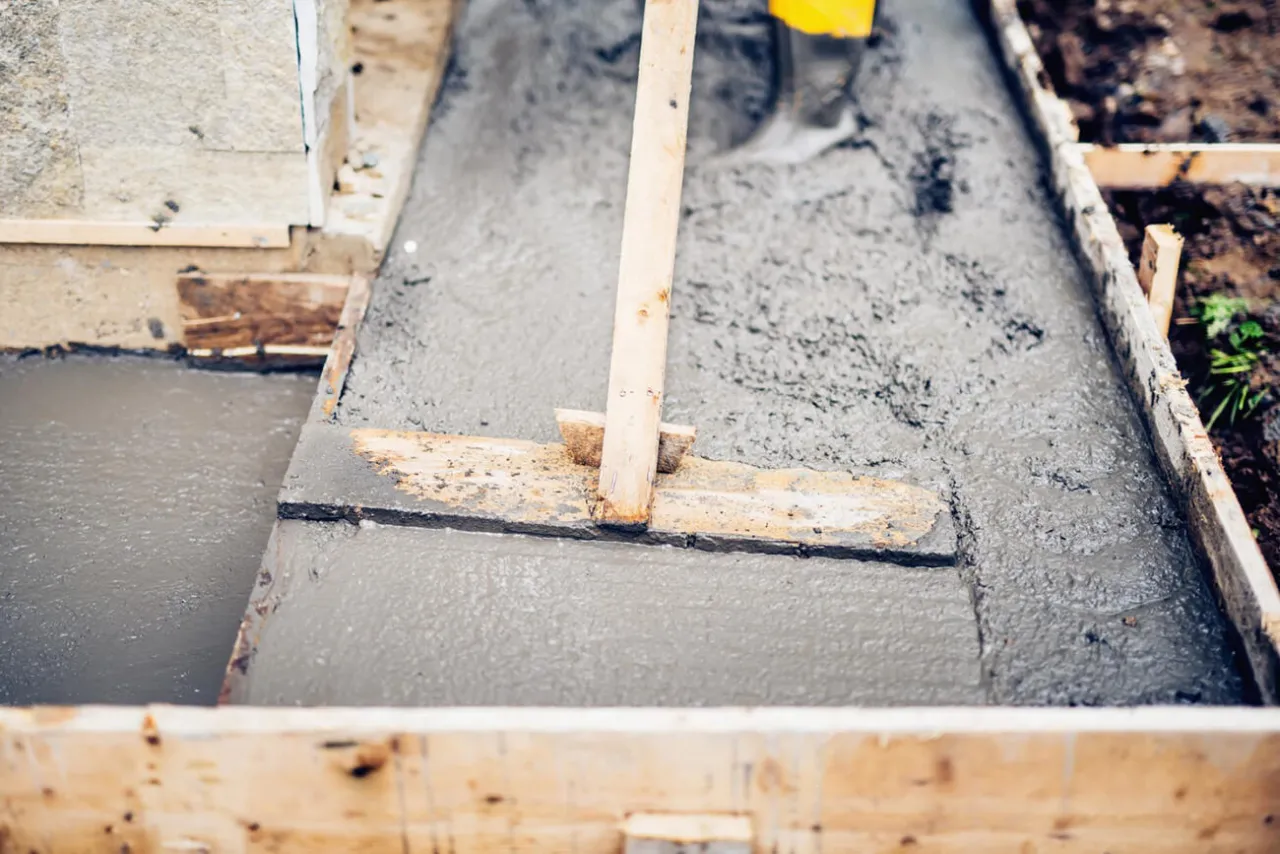 Praca z betonem, gdzie widać drewniane szalunki i świeżą masę. Zastanawiasz się, ile cementu na m3 betonu B20?