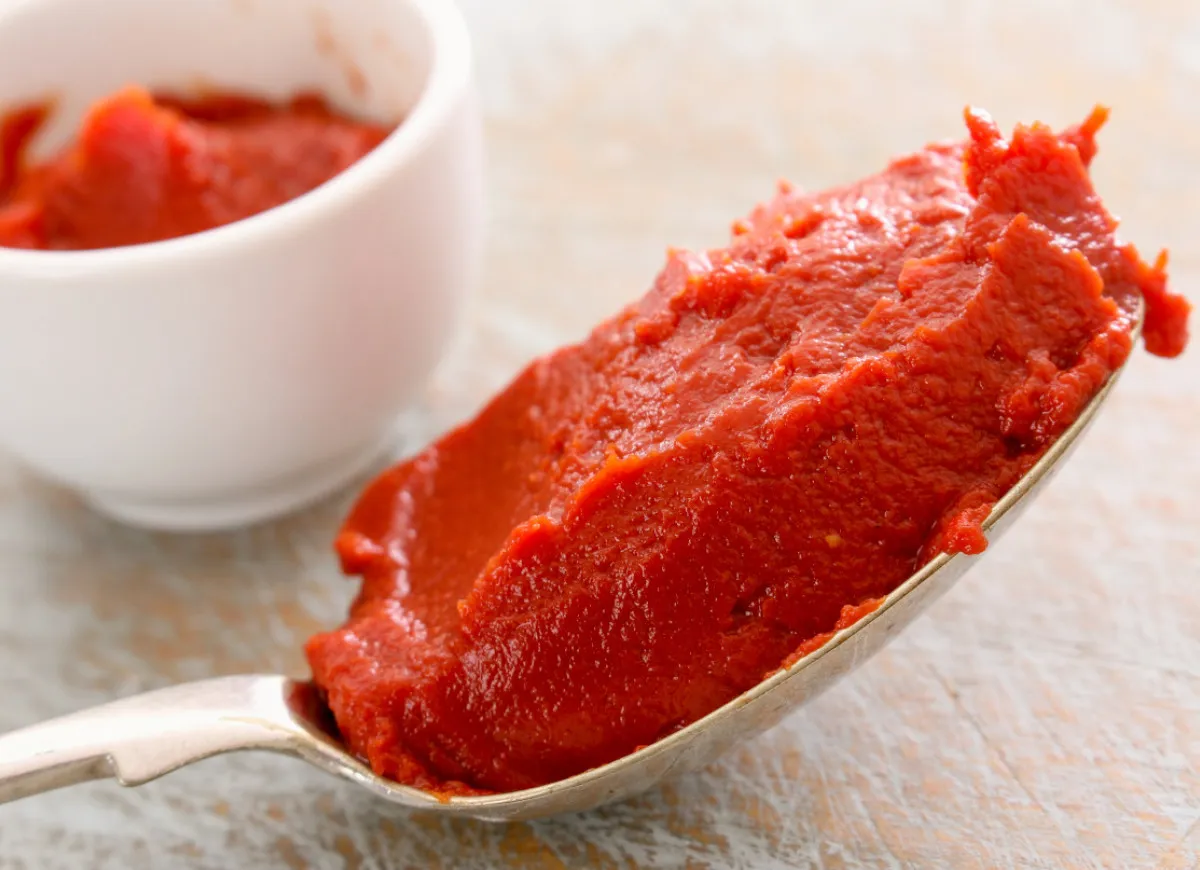 kucharz smażący koncentrat pomidorowy na patelni z oliwą