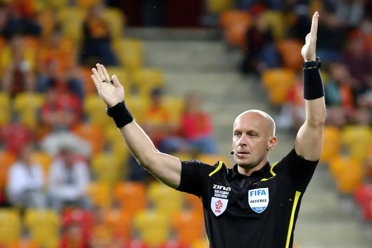 Sędzia podnosi ręce na boisku. Ciekawe, ile zarabia sędzia w Ekstraklasie za takie emocje.