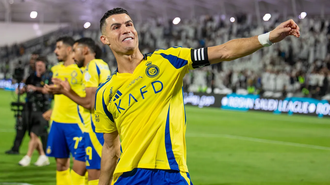 Uśmiechnięty Cristiano Ronaldo w ż&oacute;łtej koszulce Al Nassr, świętujący zwycięstwo. Jego ogromne cristiano ronaldo zarobki pozwalają mu grać w lidze saudyjskiej.