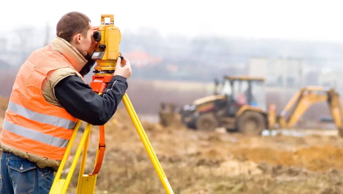 Geodeta w terenie wyznaczający punkty graniczne