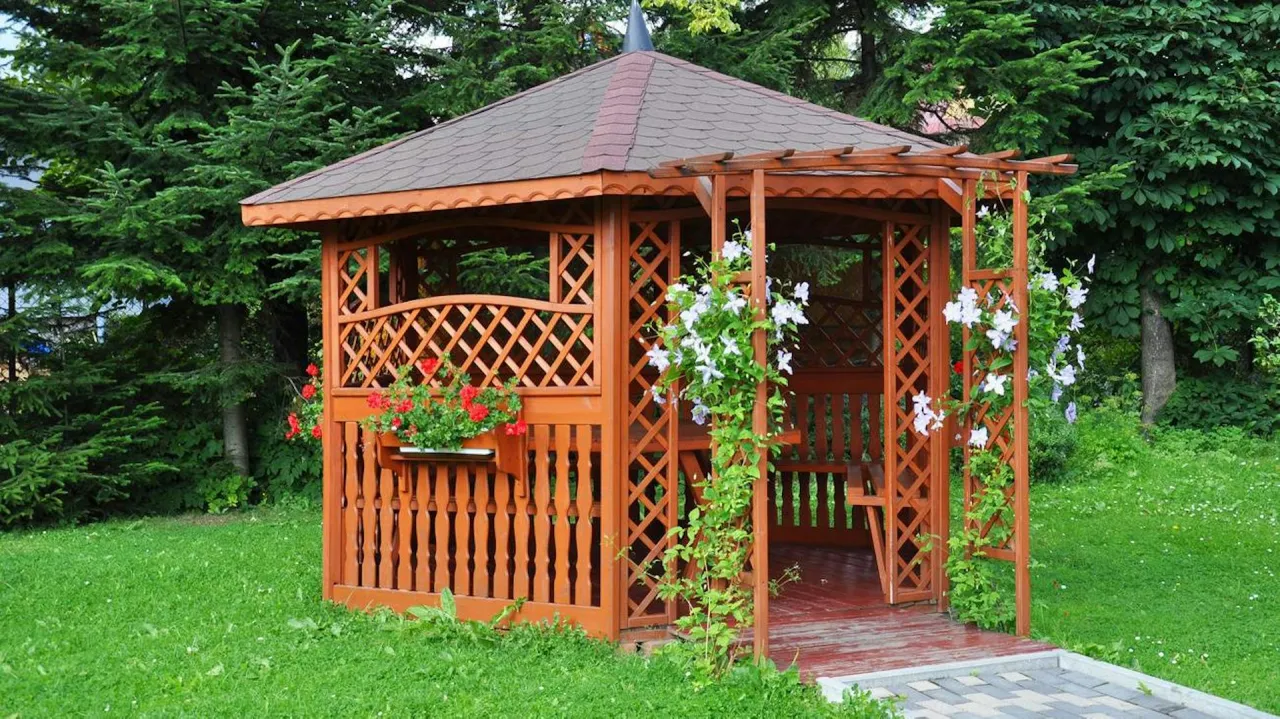 Drewniana altana ogrodowa z kwitnącymi pnączami. Zastanawiasz się, ile kosztuje altana ogrodowa? Ta prezentuje się okazale.