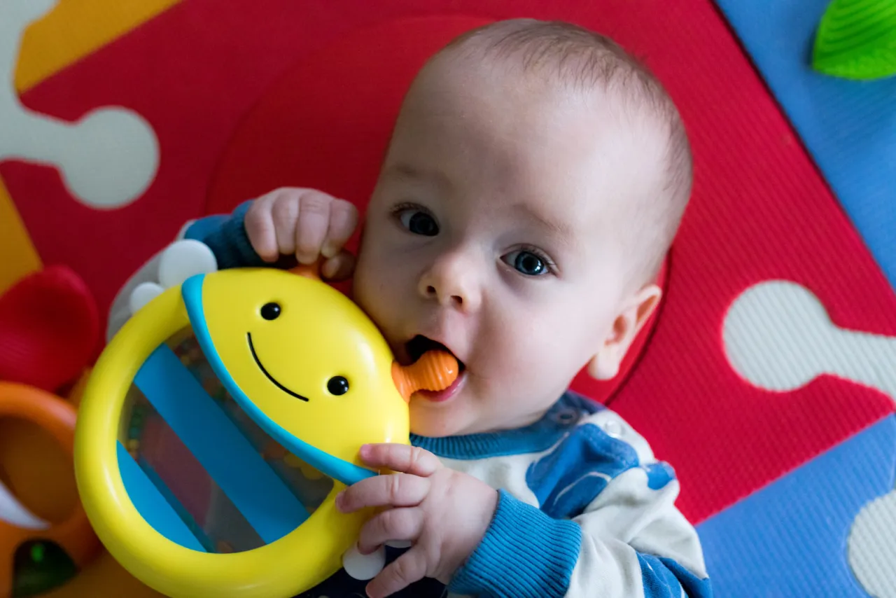 niemowlę 4 miesiące bawi się zabawkami
